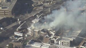 Smoke still rising, crowds gather as firefighters battle day-old 5-alarm apartment blaze